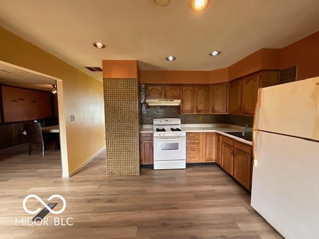 1998 Crescent St, Franklin, IN 46131 - kitchen featuring white appliances, under cabinet range hood, light wood-style floors, light countertops, and decorative backsplash