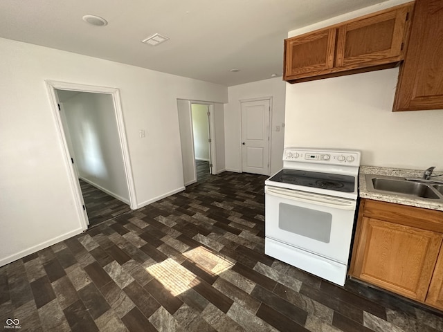 2310 E Raymond St, Indianapolis, IN 46203 - kitchen with white range with electric cooktop, a sink, light countertops, brown cabinetry, and baseboards