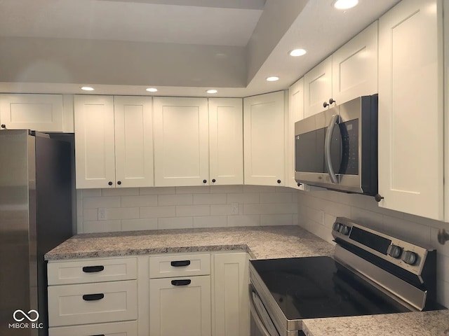 70 Lookout Ridge Dr, Columbus, IN 47201 - kitchen with appliances with stainless steel finishes, white cabinets, recessed lighting, decorative backsplash, and light stone countertops