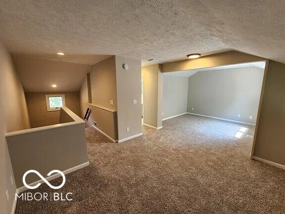 70 Lookout Ridge Dr, Columbus, IN 47201 - additional living space with vaulted ceiling, a textured ceiling, carpet floors, and baseboards