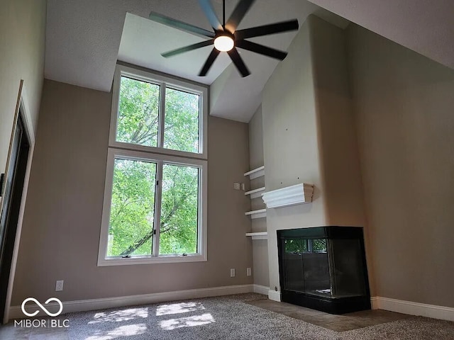 70 Lookout Ridge Dr, Columbus, IN 47201 - unfurnished living room featuring ceiling fan, high vaulted ceiling, baseboards, a glass covered fireplace, and carpet floors