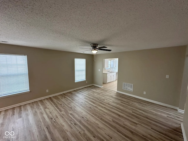 3861 Candle Berry Dr, Indianapolis, IN 46235 - empty room with a textured ceiling, wood finished floors, baseboards, a ceiling fan, and a sink