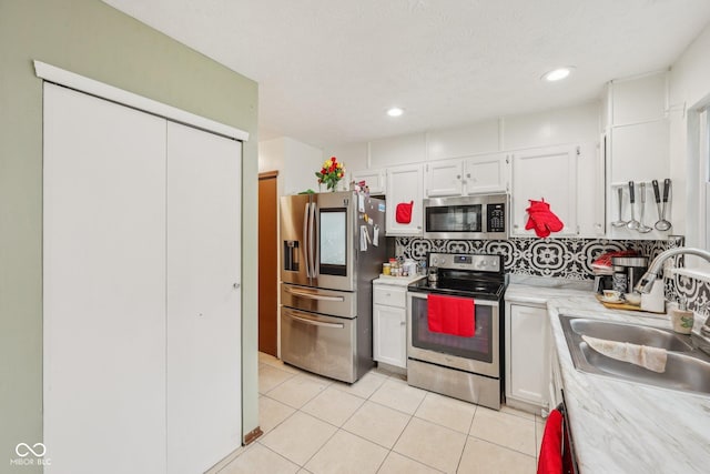 6627 Cobden Ct, Indianapolis, IN 46254 - kitchen with stainless steel appliances, white cabinets, a sink, light countertops, and light tile patterned floors