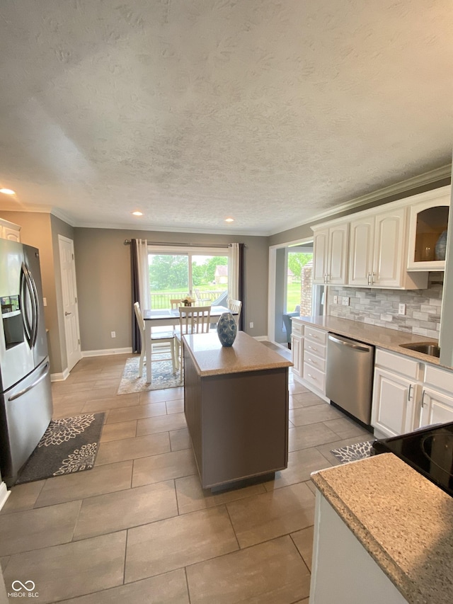 12231 Valley View Cir, Indianapolis, IN 46229 - kitchen featuring appliances with stainless steel finishes, ornamental molding, plenty of natural light, white cabinets, and decorative backsplash
