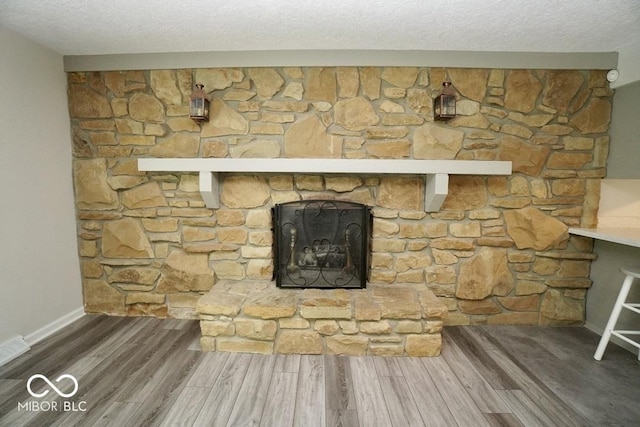 5331 Birch Ln, Greenwood, IN 46143 - detailed view of wood finished floors, baseboards, a textured ceiling, and a stone fireplace