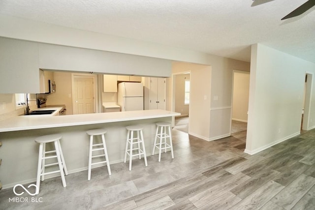 5331 Birch Ln, Greenwood, IN 46143 - kitchen featuring freestanding refrigerator, ceiling fan, light countertops, a peninsula, and a kitchen bar