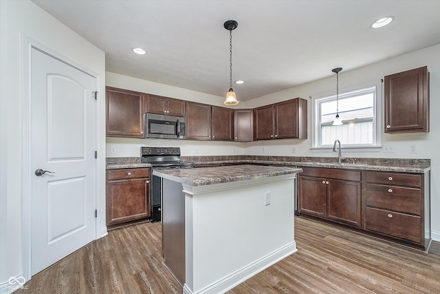 107 Elliott Ave, Trafalgar, IN 46181 - kitchen with stainless steel microwave, black electric range oven, a sink, wood finished floors, and pendant lighting
