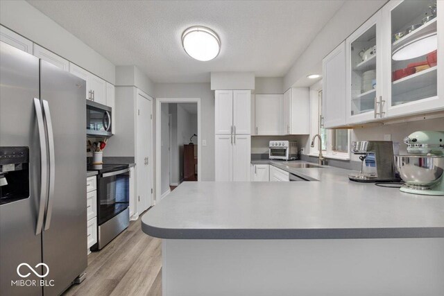 601 Woodbine, Terre Haute, IN 47803 - kitchen featuring stainless steel appliances, a sink, white cabinetry, light wood-style flooring, and a textured ceiling