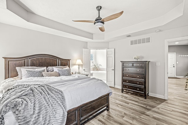 10697 Woodmont Ln, Fishers, IN 46037 - bedroom featuring a tray ceiling, light wood-type flooring, baseboards, ceiling fan, and ensuite bath