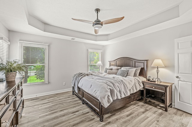 10697 Woodmont Ln, Fishers, IN 46037 - bedroom featuring light wood-type flooring, a raised ceiling, baseboards, and ceiling fan