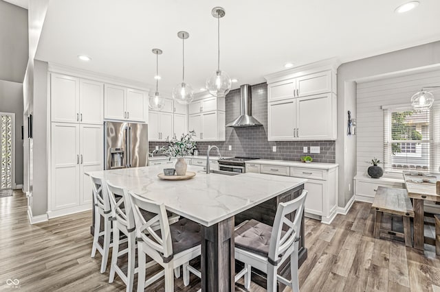 10697 Woodmont Ln, Fishers, IN 46037 - kitchen featuring stainless steel appliances, wall chimney exhaust hood, a sink, light wood-style flooring, and recessed lighting
