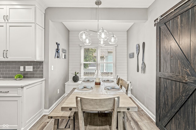 10697 Woodmont Ln, Fishers, IN 46037 - dining space featuring light wood-style flooring, a chandelier, baseboards, and a barn door