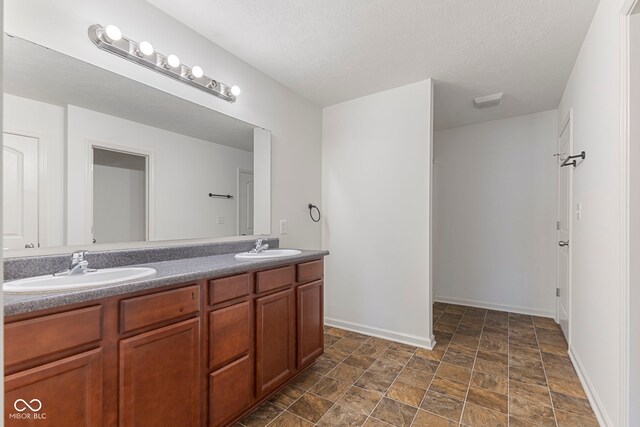 11531 Short Iron Ln, Indianapolis, IN 46235 - full bath featuring double vanity, baseboards, stone finish floors, and a textured ceiling