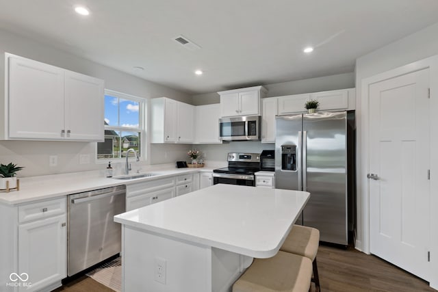 7051 E Bean Blossom Dr, Camby, IN 46113 - kitchen with appliances with stainless steel finishes, a sink, a kitchen island, a kitchen bar, and white cabinetry
