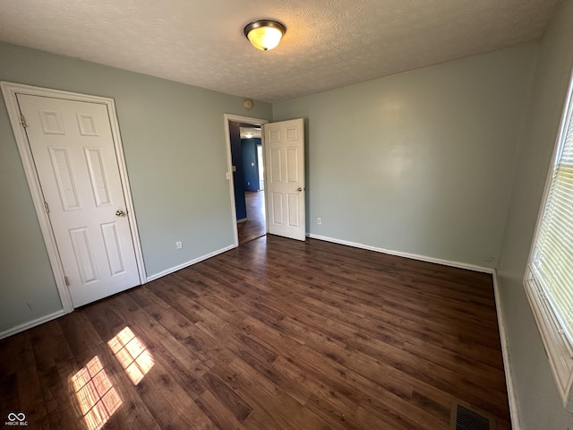 2133 10th St, Columbus, IN 47201 - unfurnished bedroom featuring dark wood-type flooring, baseboards, and a textured ceiling