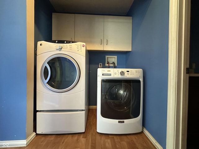 2133 10th St, Columbus, IN 47201 - washroom featuring washer and clothes dryer, cabinet space, wood finished floors, and baseboards