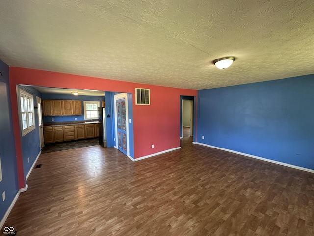 2133 10th St, Columbus, IN 47201 - unfurnished living room with dark wood-style flooring, a textured ceiling, and baseboards