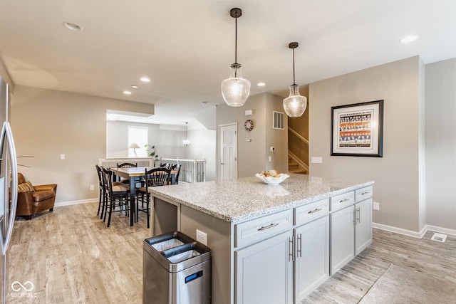 16072 Barringer Ct, Westfield, IN 46074 - kitchen with light wood-style flooring, a center island, recessed lighting, decorative light fixtures, and light stone counters