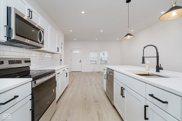 2909 E Michigan St, Indianapolis, IN 46201 - kitchen with appliances with stainless steel finishes, a sink, backsplash, light wood-style flooring, and pendant lighting