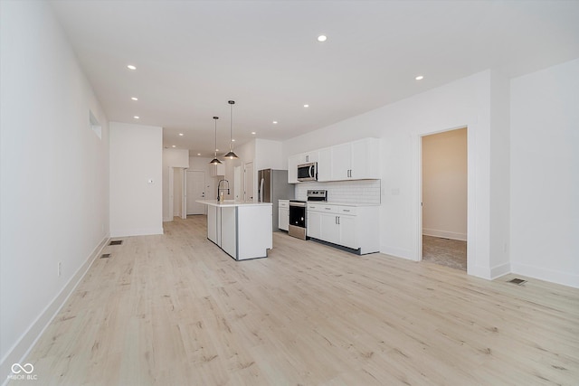 2909 E Michigan St, Indianapolis, IN 46201 - kitchen with appliances with stainless steel finishes, a sink, a center island with sink, white cabinetry, and light wood finished floors
