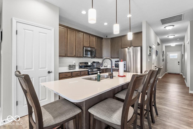 104 Perlican Dr, Cicero, IN 46034 - kitchen featuring appliances with stainless steel finishes, a sink, a kitchen bar, wood finished floors, and pendant lighting