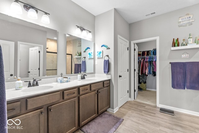 104 Perlican Dr, Cicero, IN 46034 - bathroom with double vanity, tiled shower, wood finished floors, a spacious closet, and baseboards
