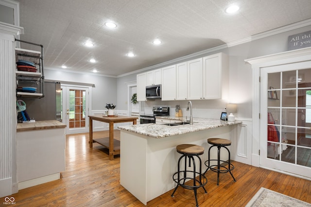 2708 N 400 E, Greenfield, IN 46140 - kitchen with appliances with stainless steel finishes, ornamental molding, light wood-type flooring, white cabinetry, and a sink