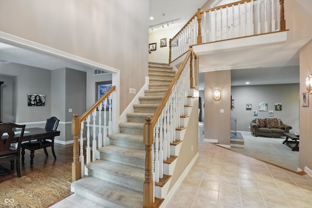 7138 Nile Ridge Ct, Indianapolis, IN 46236 - staircase featuring a towering ceiling, baseboards, rail lighting, and tile patterned floors