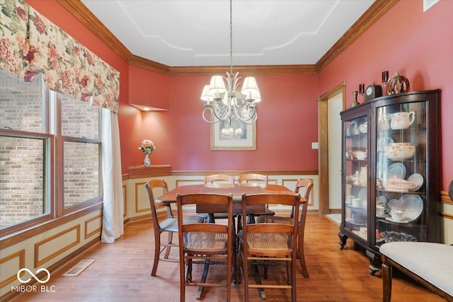 6363 Harmonridge Ct, Indianapolis, IN 46278 - dining area with wood finished floors, a chandelier, ornamental molding, a wainscoted wall, and a decorative wall