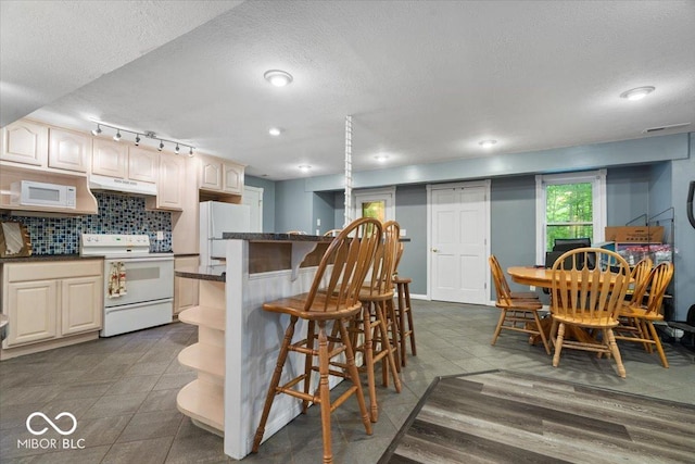 6363 Harmonridge Ct, Indianapolis, IN 46278 - kitchen with white appliances, under cabinet range hood, dark countertops, a kitchen breakfast bar, and a center island
