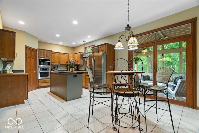 6363 Harmonridge Ct, Indianapolis, IN 46278 - kitchen featuring stainless steel appliances, a kitchen island, light tile patterned floors, recessed lighting, and brown cabinetry