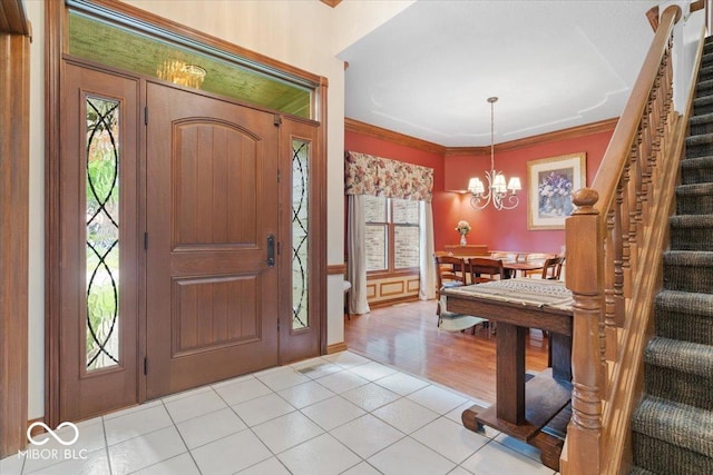 6363 Harmonridge Ct, Indianapolis, IN 46278 - foyer entrance featuring stairway, a chandelier, light tile patterned floors, and ornamental molding