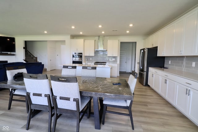 9640 Katana Cir, Fishers, IN 46040 - kitchen with wall chimney exhaust hood, appliances with stainless steel finishes, an island with sink, light countertops, and tasteful backsplash