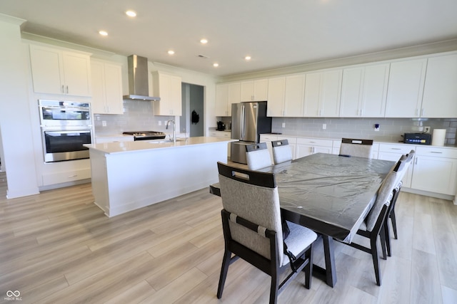 9640 Katana Cir, Fishers, IN 46040 - kitchen featuring wall chimney exhaust hood, stainless steel appliances, a kitchen island with sink, decorative backsplash, and light countertops