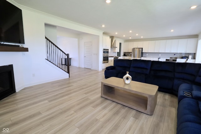 9640 Katana Cir, Fishers, IN 46040 - living area featuring light wood-style flooring, stairs, recessed lighting, and a glass covered fireplace