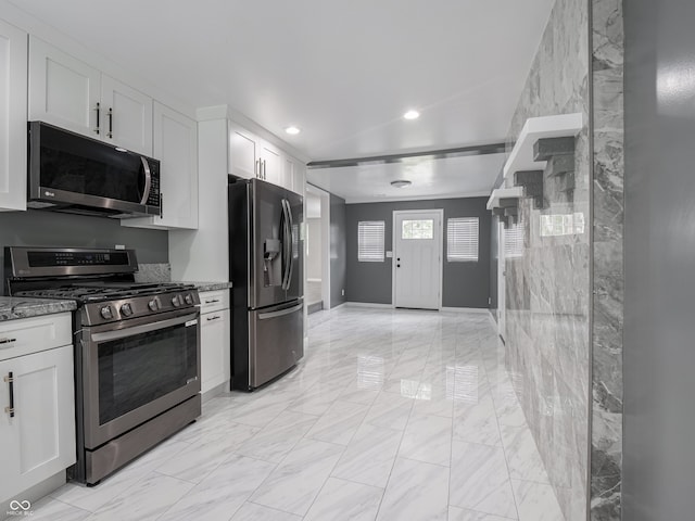 1141 Temperance Ave, Indianapolis, IN 46203 - kitchen featuring appliances with stainless steel finishes, light stone countertops, white cabinets, light marble finish floors, and recessed lighting