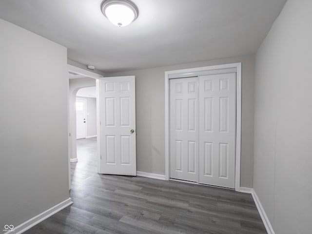1141 Temperance Ave, Indianapolis, IN 46203 - unfurnished bedroom featuring arched walkways, dark wood finished floors, and baseboards