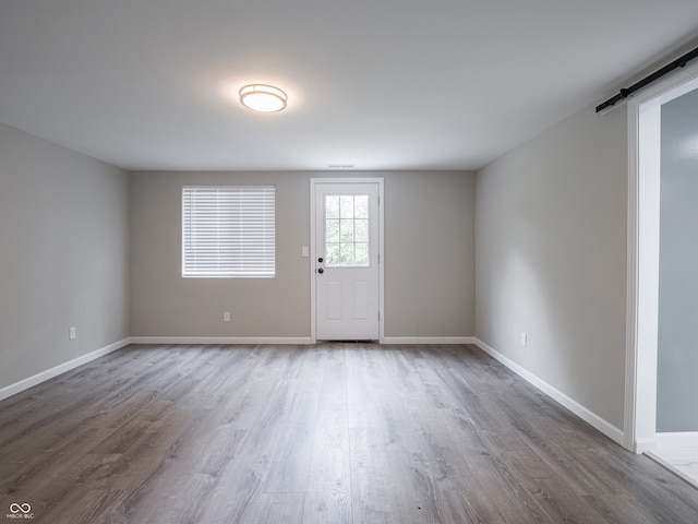 1141 Temperance Ave, Indianapolis, IN 46203 - unfurnished room featuring a barn door, wood finished floors, and baseboards
