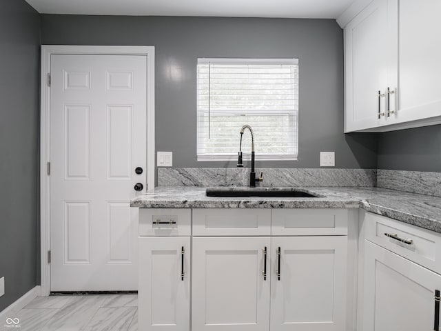 1141 Temperance Ave, Indianapolis, IN 46203 - kitchen with a sink, light marble finish floors, white cabinets, and light stone counters
