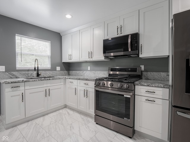 1141 Temperance Ave, Indianapolis, IN 46203 - kitchen with appliances with stainless steel finishes, a sink, white cabinetry, light stone countertops, and recessed lighting