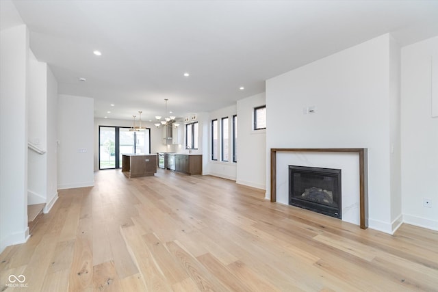 1822 Central Ave, Indianapolis, IN 46202 - unfurnished living room featuring a chandelier, light wood finished floors, recessed lighting, a glass covered fireplace, and baseboards