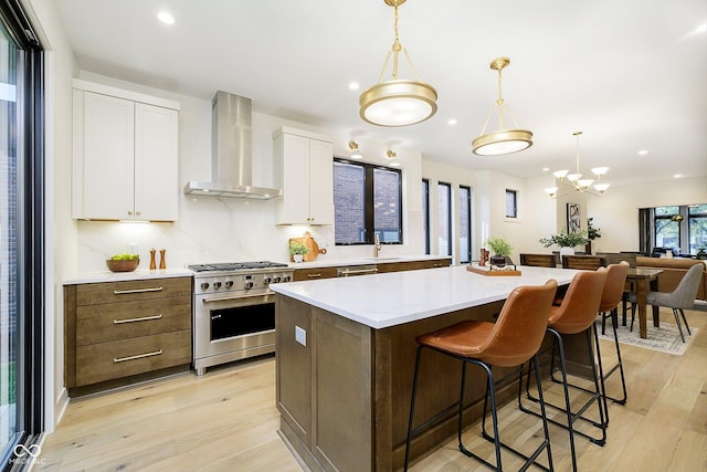 1822 Central Ave, Indianapolis, IN 46202 - kitchen featuring appliances with stainless steel finishes, wall chimney range hood, a kitchen island, light wood-type flooring, and recessed lighting