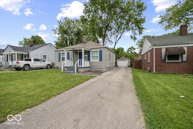 1907 N Drexel Ave, Indianapolis, IN 46218 - bungalow-style home featuring an outbuilding, a garage, driveway, a chimney, and a front lawn