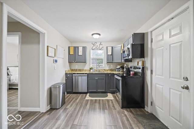 1907 N Drexel Ave, Indianapolis, IN 46218 - kitchen with appliances with stainless steel finishes, wood finished floors, baseboards, gray cabinets, and a sink