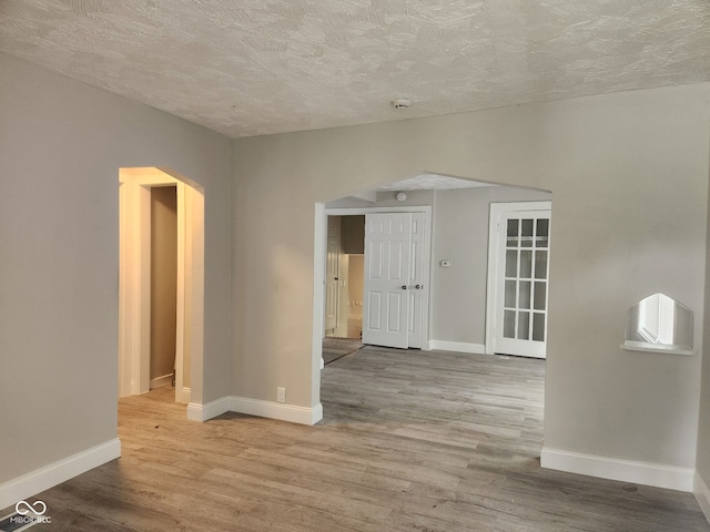 1624 E 30th St, Indianapolis, IN 46218 - spare room featuring arched walkways, a textured ceiling, wood finished floors, baseboards, and a smoke detector