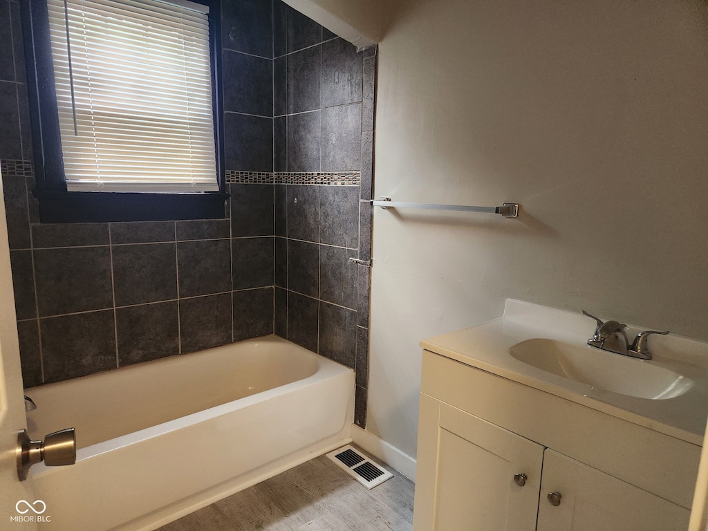 1624 E 30th St, Indianapolis, IN 46218 - bathroom with baseboards, vanity, shower / bathtub combination, and wood finished floors