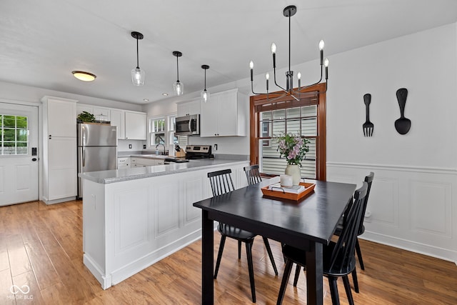 1438 Adams St, Lafayette, IN 47905 - dining room featuring light wood-style flooring, a chandelier, and a wainscoted wall