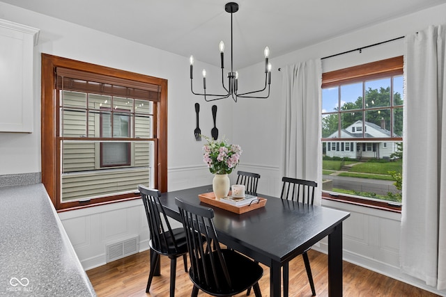 1438 Adams St, Lafayette, IN 47905 - dining room with a chandelier, a decorative wall, light wood-type flooring, and wainscoting
