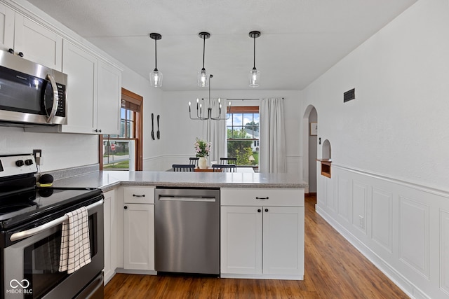 1438 Adams St, Lafayette, IN 47905 - kitchen with stainless steel appliances, a peninsula, arched walkways, a chandelier, and white cabinets
