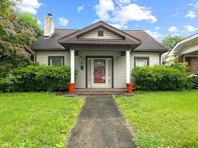 63 S 20th St, Terre Haute, IN 47803 - bungalow with covered porch, a front yard, a chimney, and roof with shingles